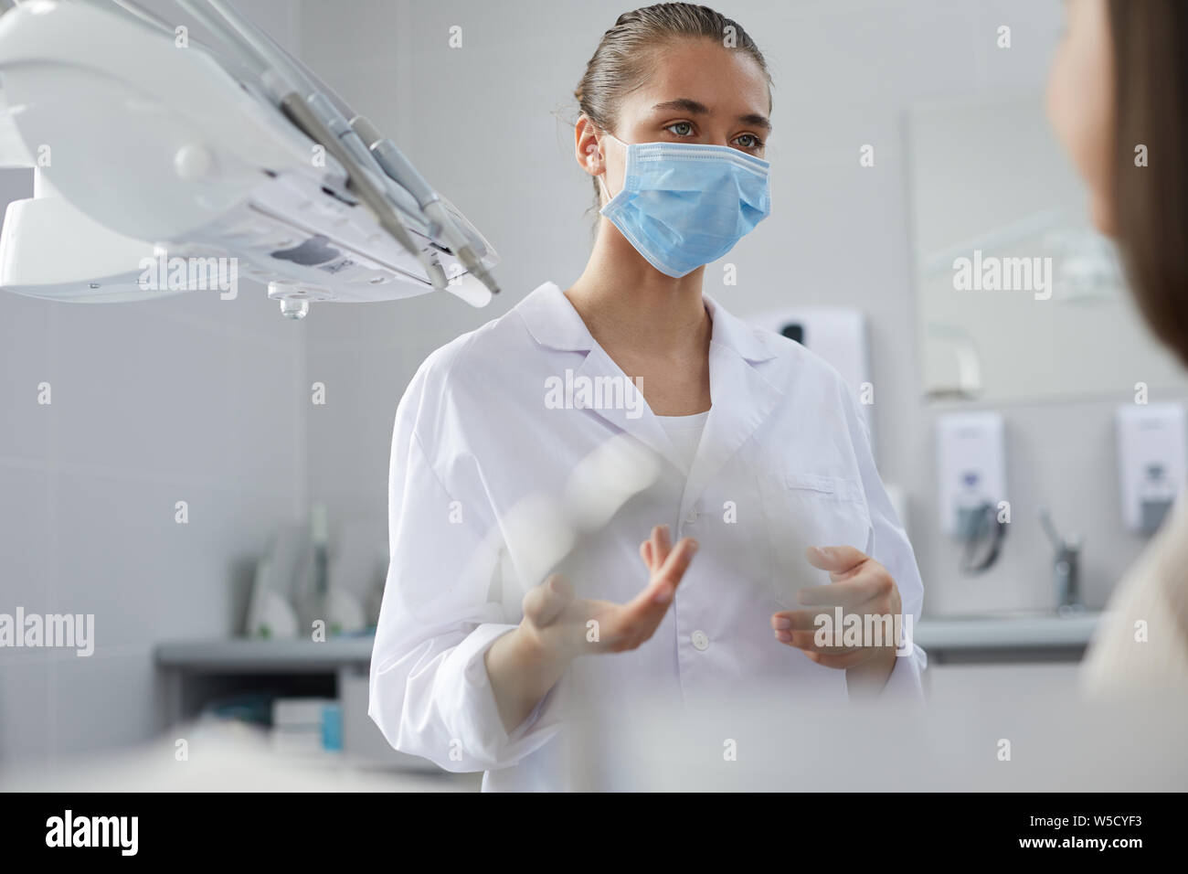 Portrait de jeune femme dentiste portant masque de protection patient dans un centre de consultation, copy space Banque D'Images