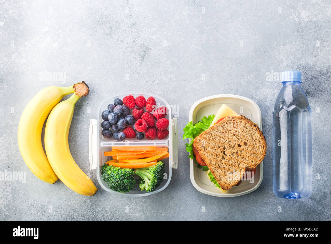 School lunch box sandwich avec de l'eau Légumes et fruits amandes sur table gris en bonne santé Banque D'Images