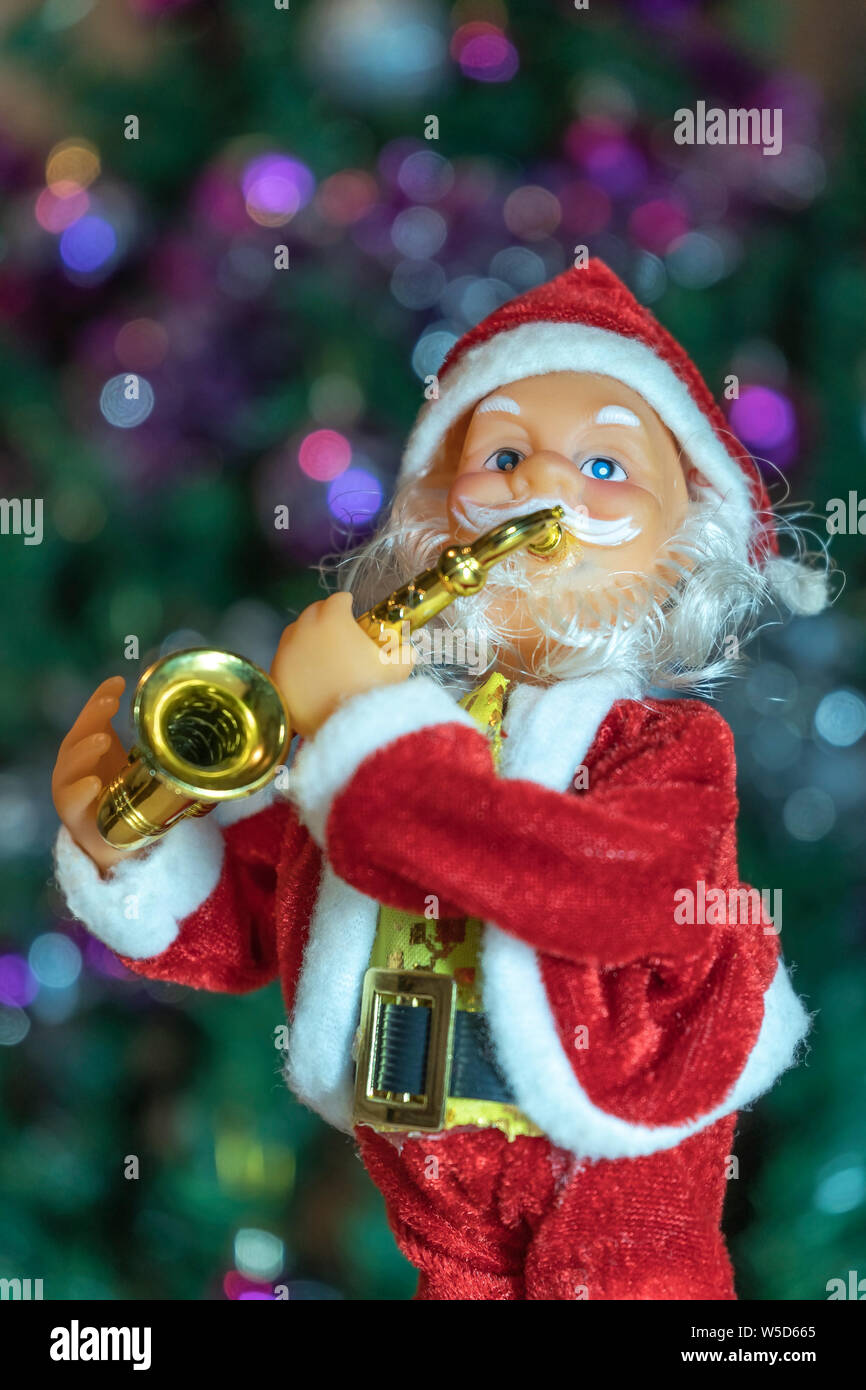 Le Père Noël joue de la trompette pour une nouvelle année et un Noël dans l'arrière-plan est vu par des couleurs vives de lumières différentes Banque D'Images