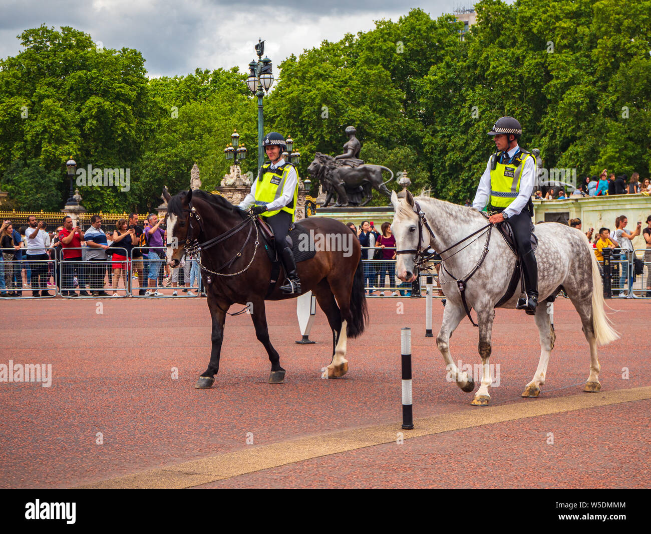 La police montée à cheval patrouillant à l'extérieur de Buckingham Palace en Angleterre entouré par des foules de touristes Banque D'Images