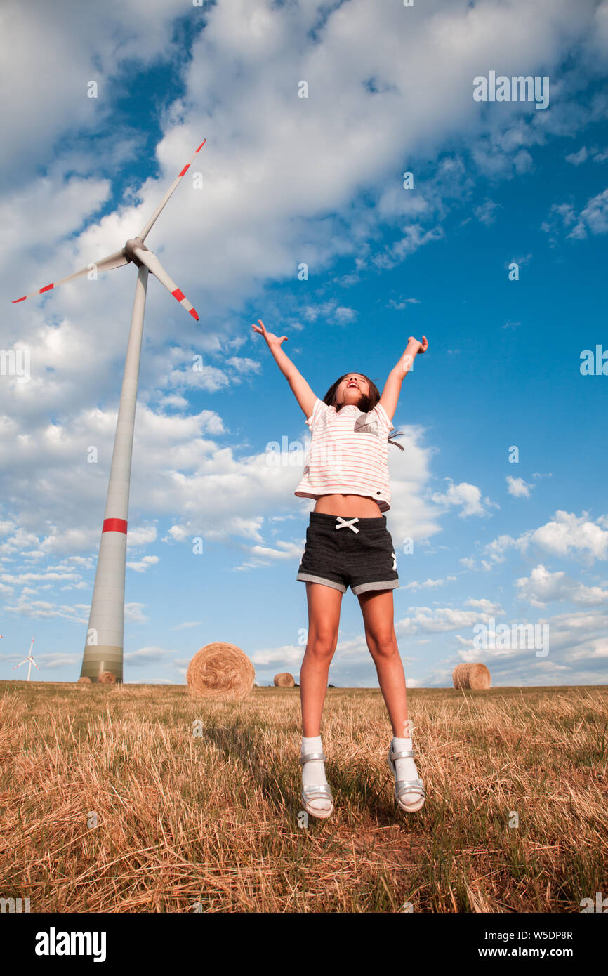 Jeu de fille et d'aller dans le champ ensoleillé avec moulin à vent. Banque D'Images