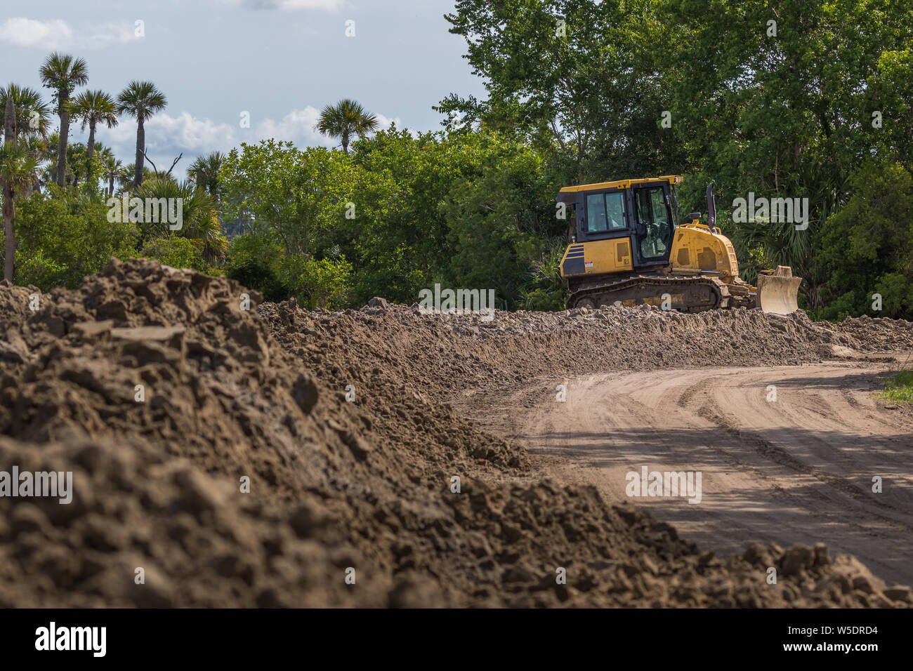 Véhicule de construction - Chargeur avant. Chargeur vide est assis à côté d'un chemin de terre dans les bois. Banque D'Images