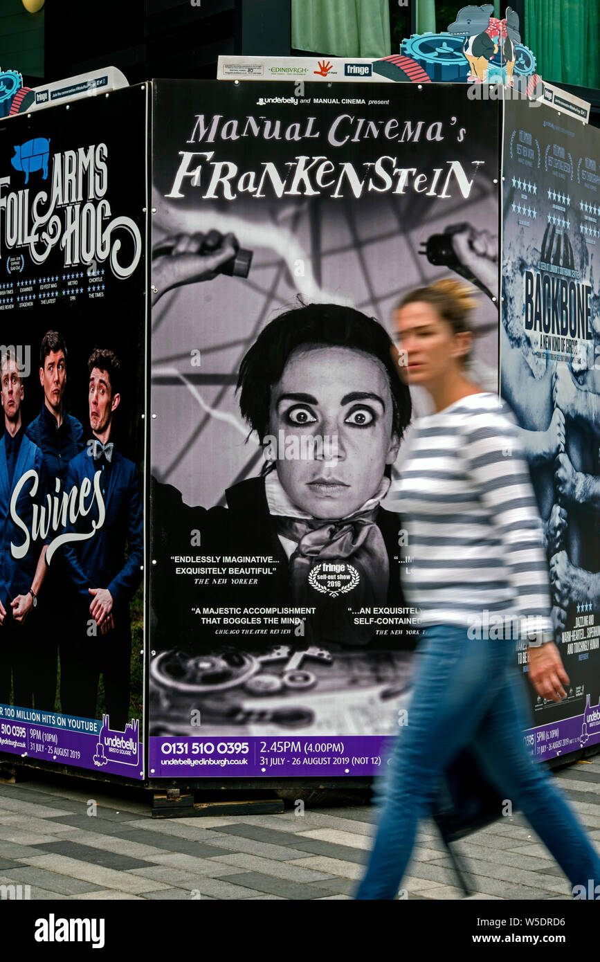 Une femme marchant par affiches publicitaires pour Edinburgh Fringe Festival montre. Edinburgh, Ecosse, Royaume-Uni. (With motion blur) Banque D'Images