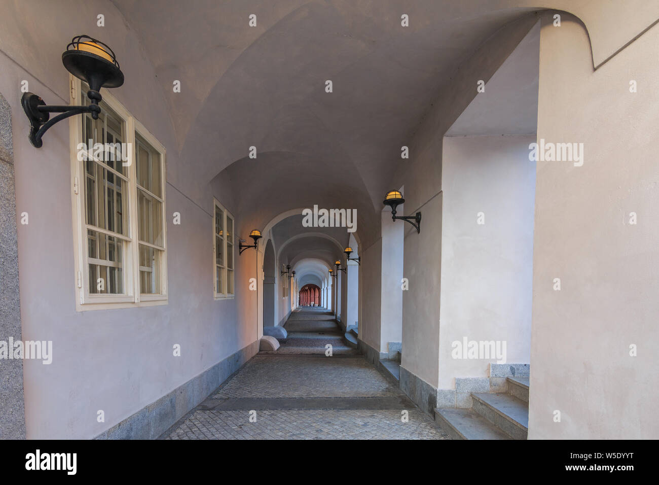 Passage en chambre semi-circulaire avec de couleur blanche avec des lampes sur les murs à Prague sur le Hradcany Square. Windows historique sur le mur. Pavage en pierre Banque D'Images