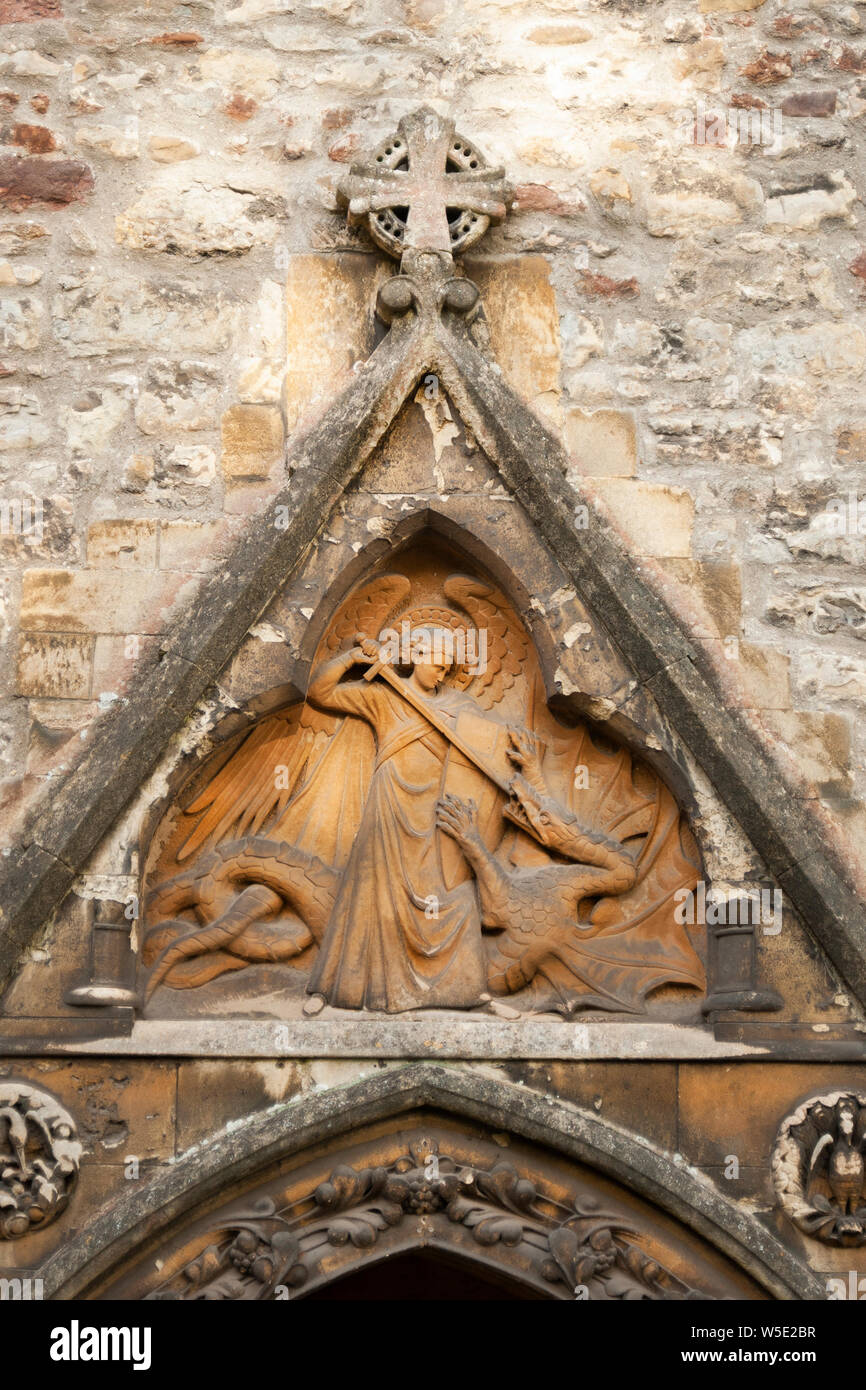 Saint Michael vaincre le dragon Satan, Christian sculpture sur pierre sur le côté de la cathédrale de Llandaff, Cardiff au Pays de Galles Banque D'Images