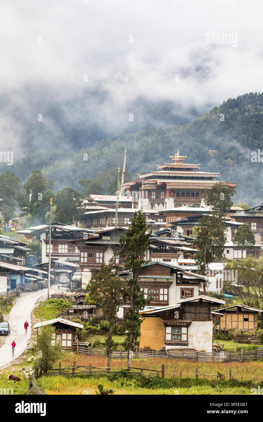 Deux chiffres, un moine, à pied jusqu'à la route à travers le village pour le Monastère de Gangtey en vallée de Phobjikha, Bhoutan Banque D'Images