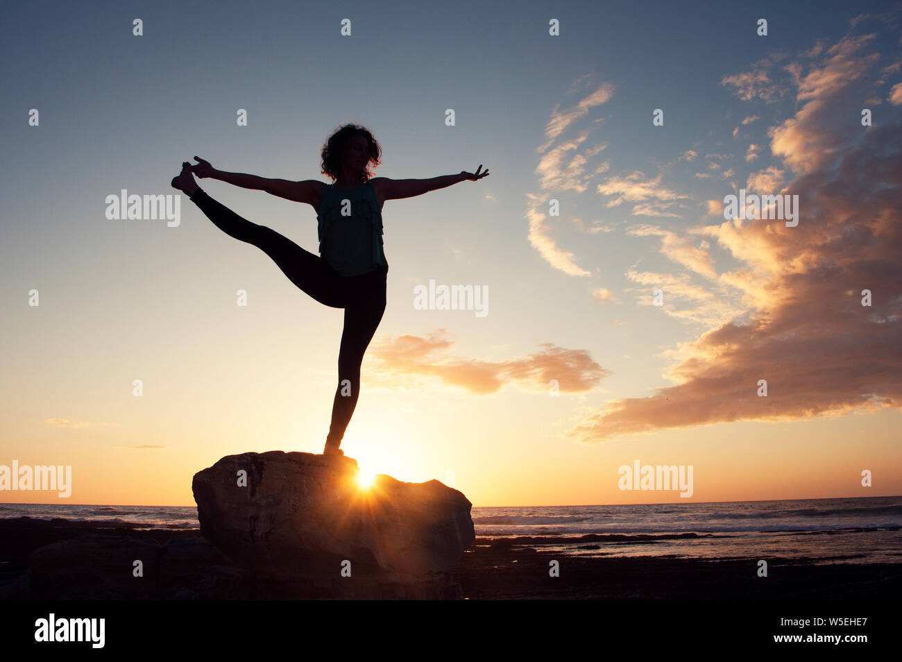 Coucher de yoga sur la plage avec happy woman yogi. Banque D'Images