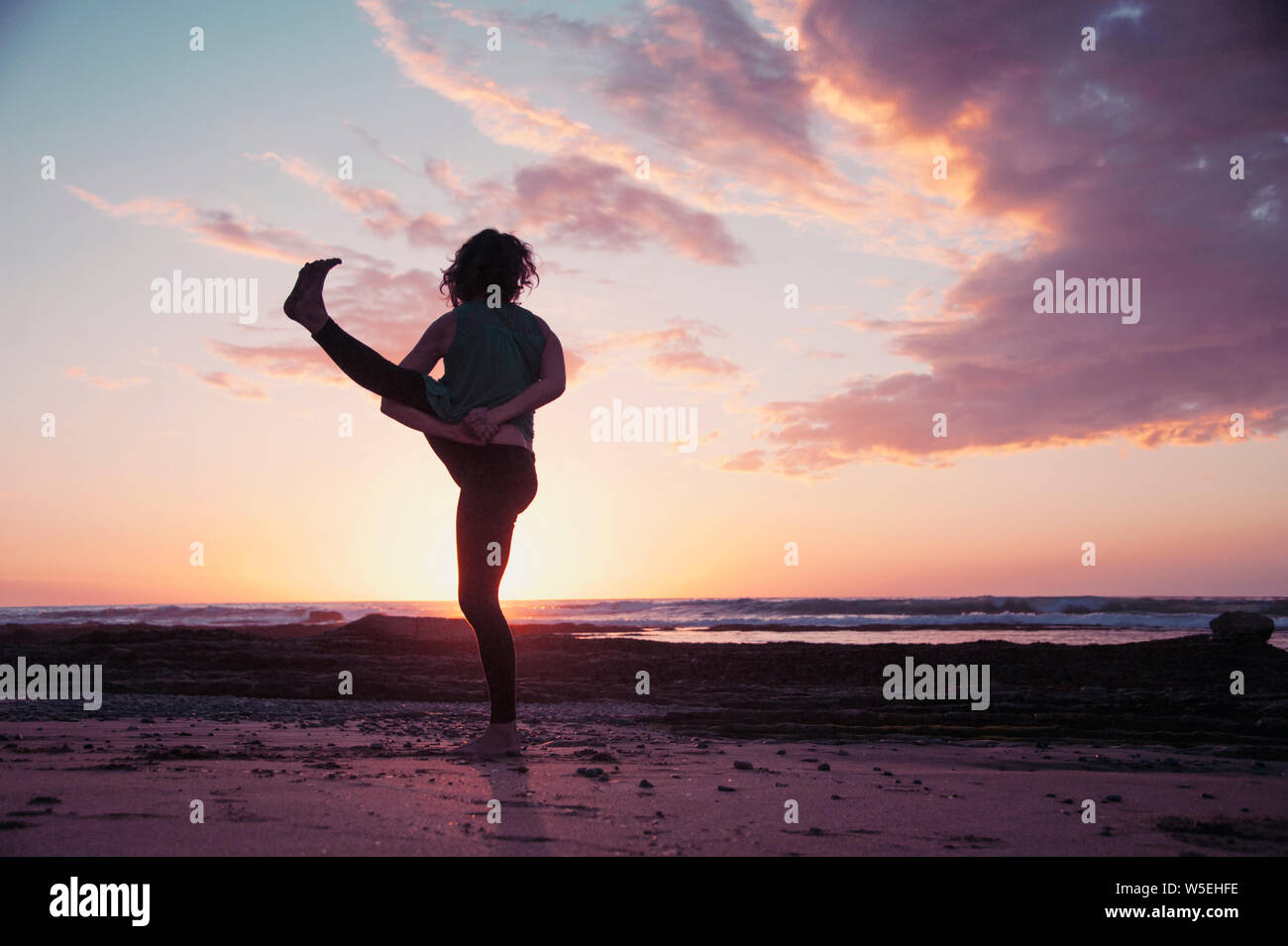 Coucher de yoga sur la plage avec happy woman yogi. Banque D'Images