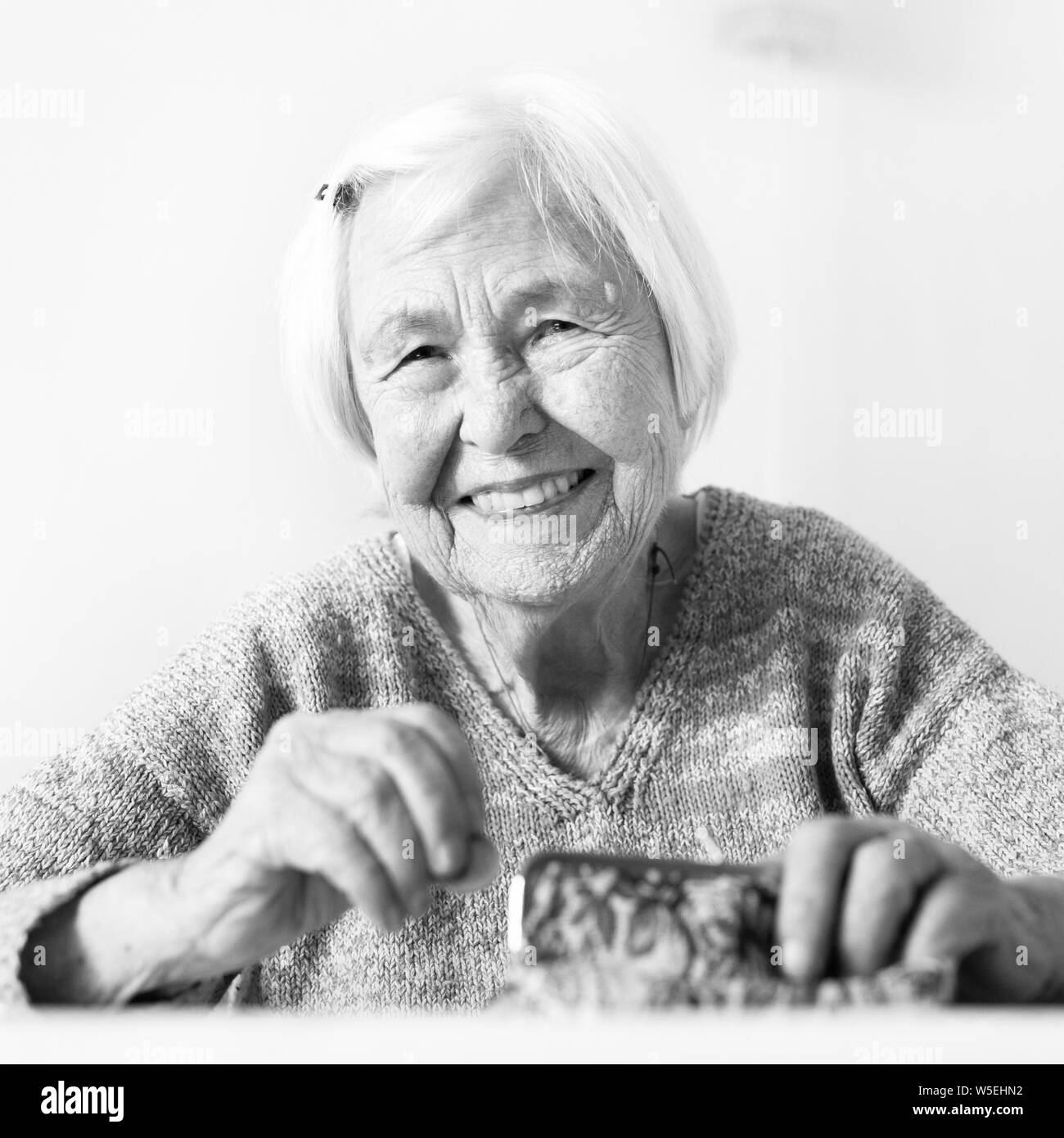 Personnes âgées gaies 96 ans woman sitting at table à la maison heureux avec elle dans son portefeuille d'épargne-retraite après le paiement des factures. Noir et blanc. Banque D'Images