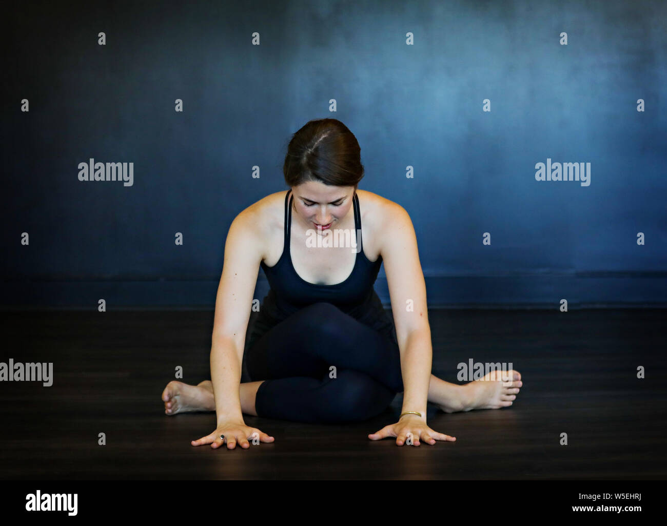 Une belle jeune brunette femme blanche n'postures de yoga sur un fond sombre. Banque D'Images
