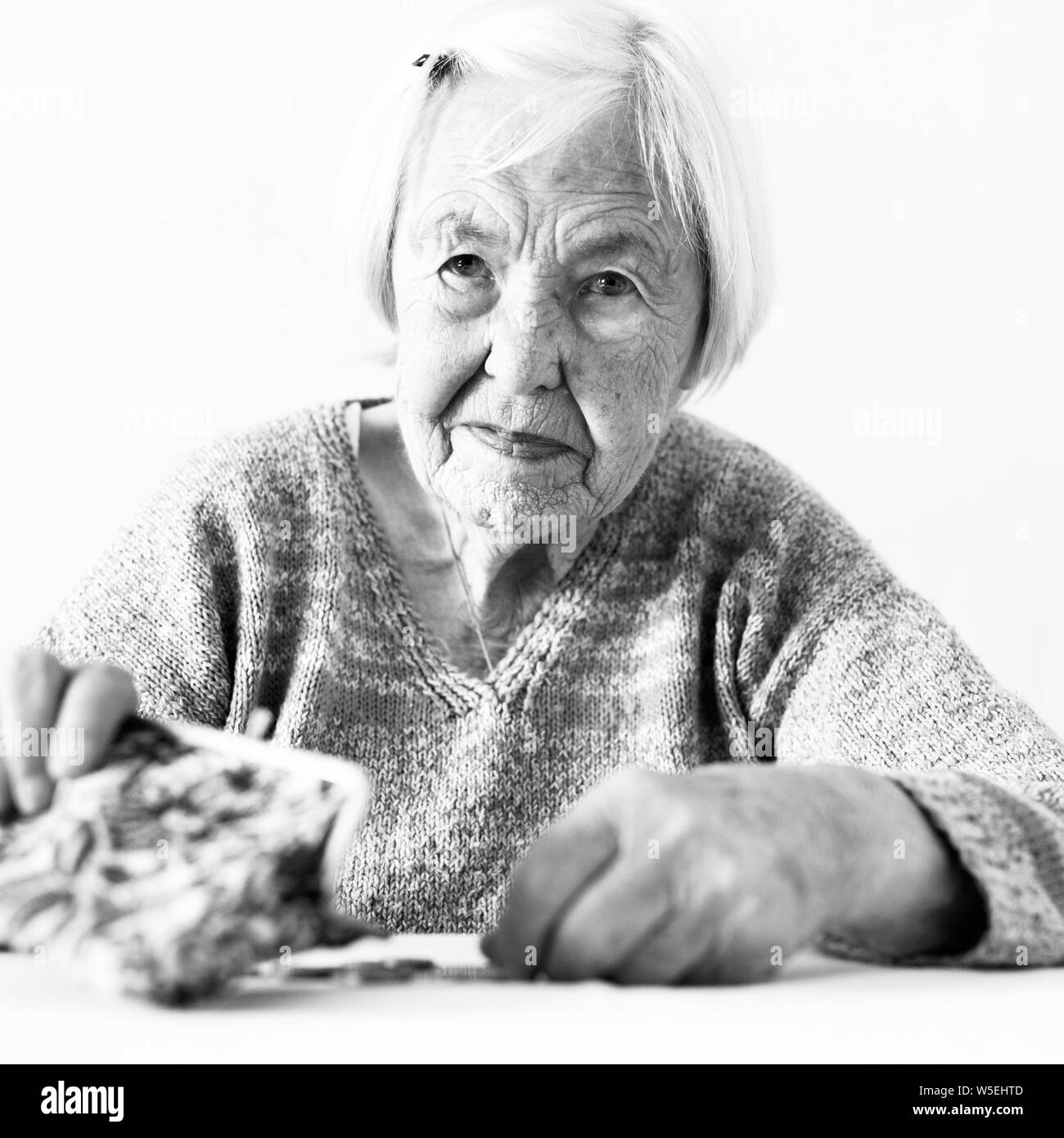 Concernés femme âgée assise à la table en comptant l'argent dans son portefeuille. Photo en noir et blanc. Banque D'Images