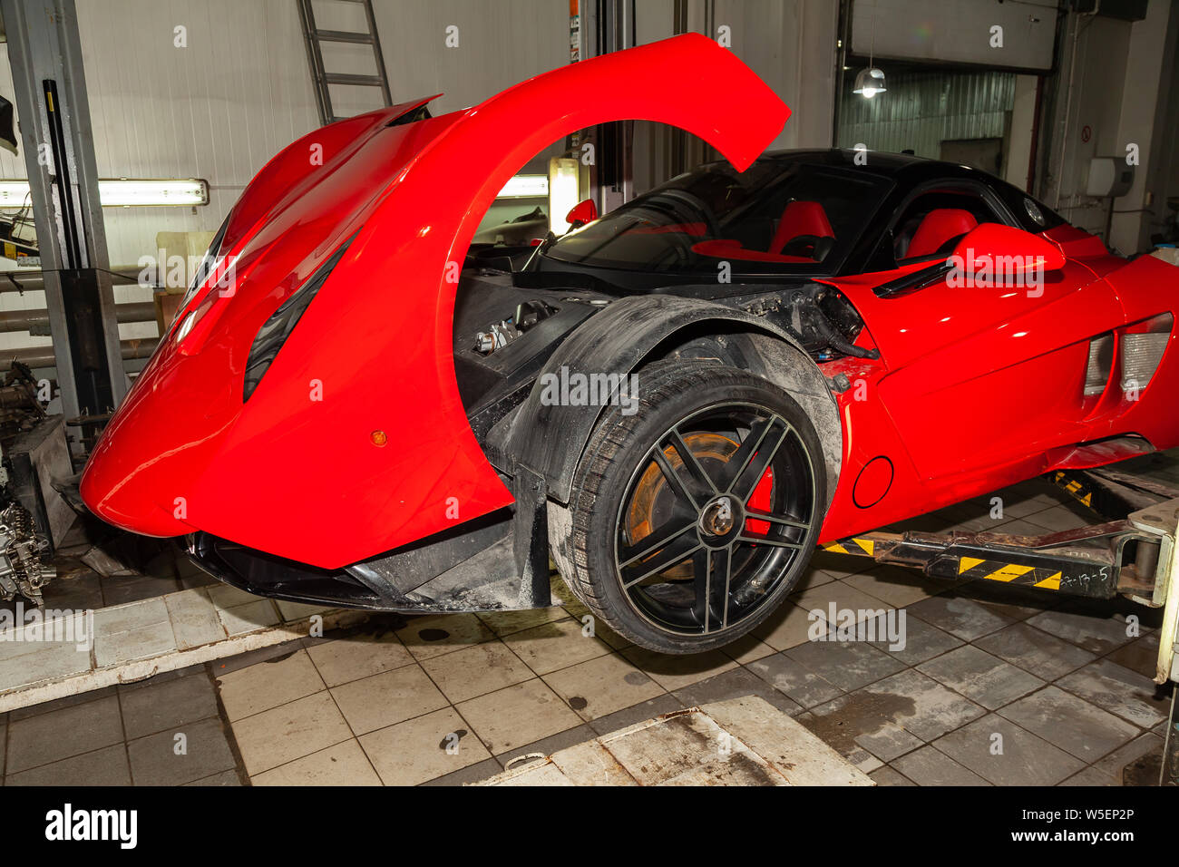 Novosibirsk, Russie - 07,25.2019 : voiture sport rouge Marussia B1 posée sur un pont dans un atelier de réparation automobile, pare-chocs arrière et becquet Banque D'Images