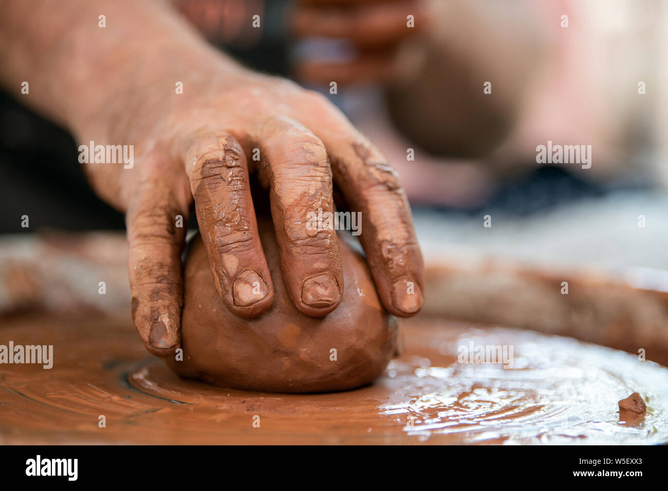 Les mains de potter. Le potter qui fait des plats de poterie sur tour de potier. Le sculpteur à l'atelier d'argile rend libre Banque D'Images