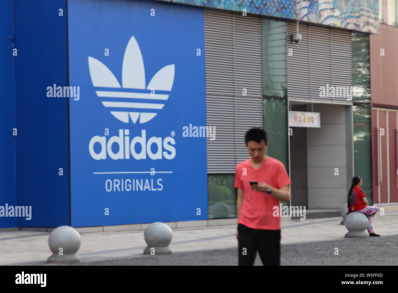 FILE--un résident local passe devant une publicité pour Adidas à Chongqing,  Chine, le 28 août 2018. Adidas a augmenté sa monnaie annuelle t Photo Stock  - Alamy