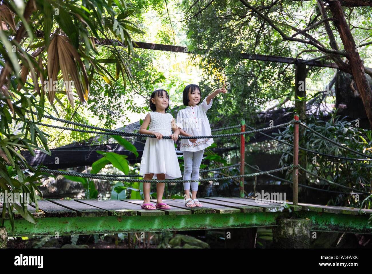 Peu d'asiatiques Sœurs chinois debout sur le pont de bois dans un jardin Banque D'Images