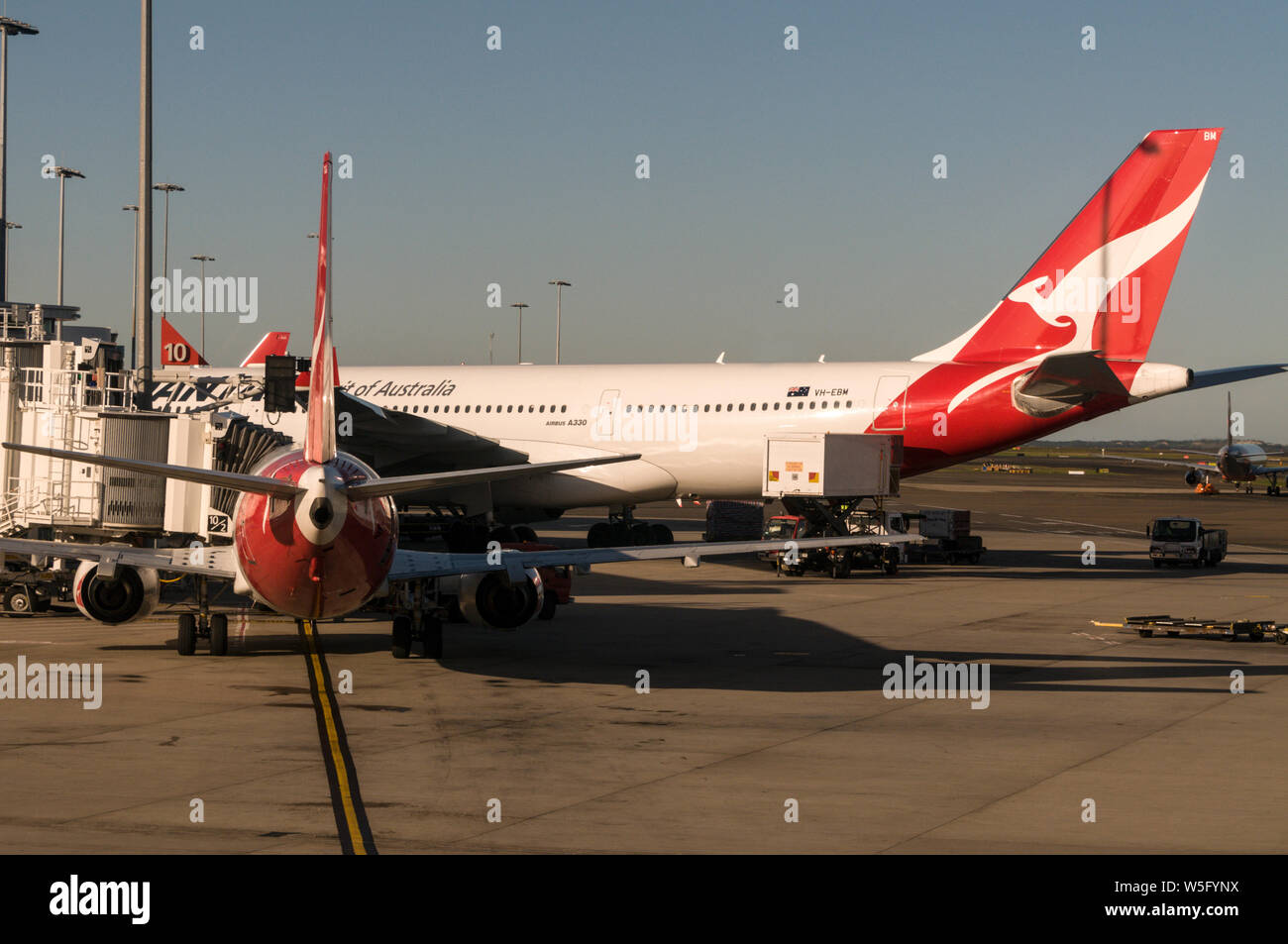 Un Qantas Airbus 330 et un petit avion à l'aérogare des vols intérieurs à Sydney (l'aéroport Kingsford Smith) près de Sydney en Nouvelle-Galles du Sud, Australie Banque D'Images