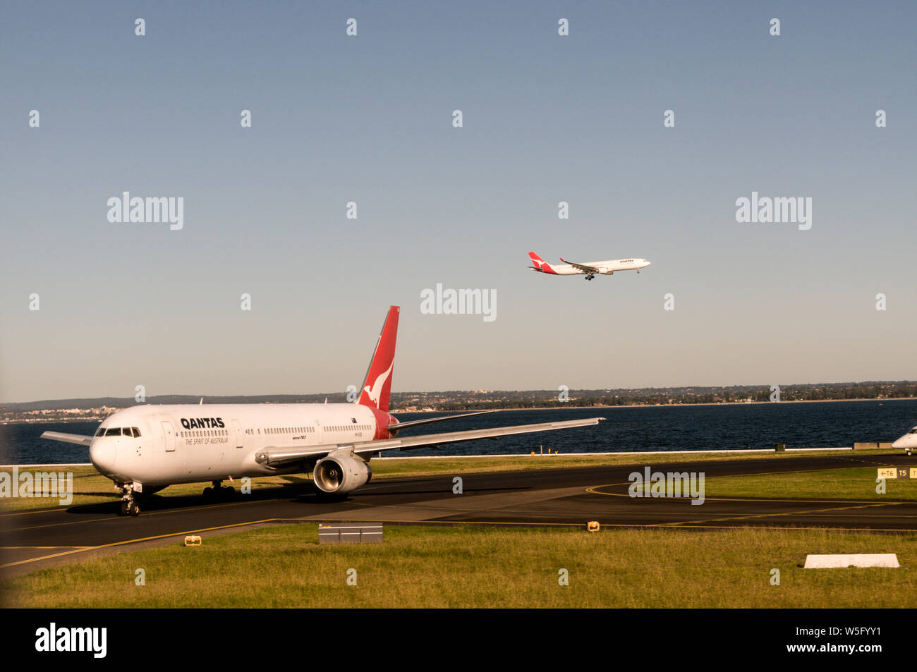 Un Boeing 767 de Qantas roulement au décollage que l'autre fait une approche à l'atterrissage à Sydney Kingsford Smith) (l'aéroport près de Sydney en Nouvelle Galles du Sud, Australie Banque D'Images
