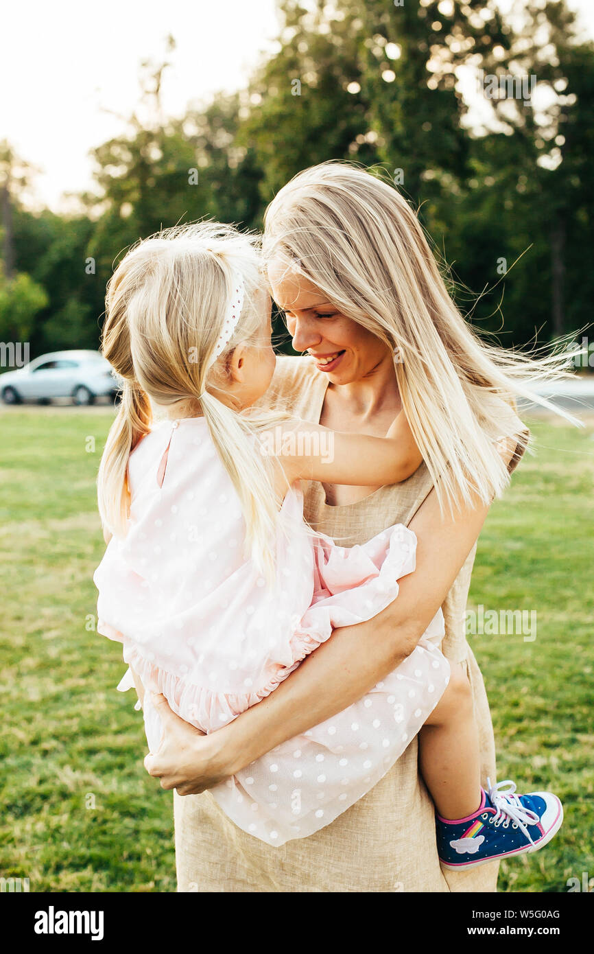 Jeune mère de levage et sa fille heureuse dans ses bras les deux smiling Banque D'Images