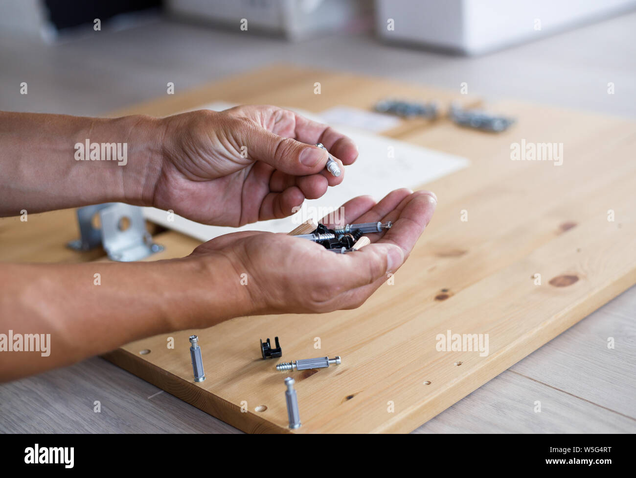 Homme montage de meubles à domicile, homme de main avec des chevilles et des vis. Banque D'Images
