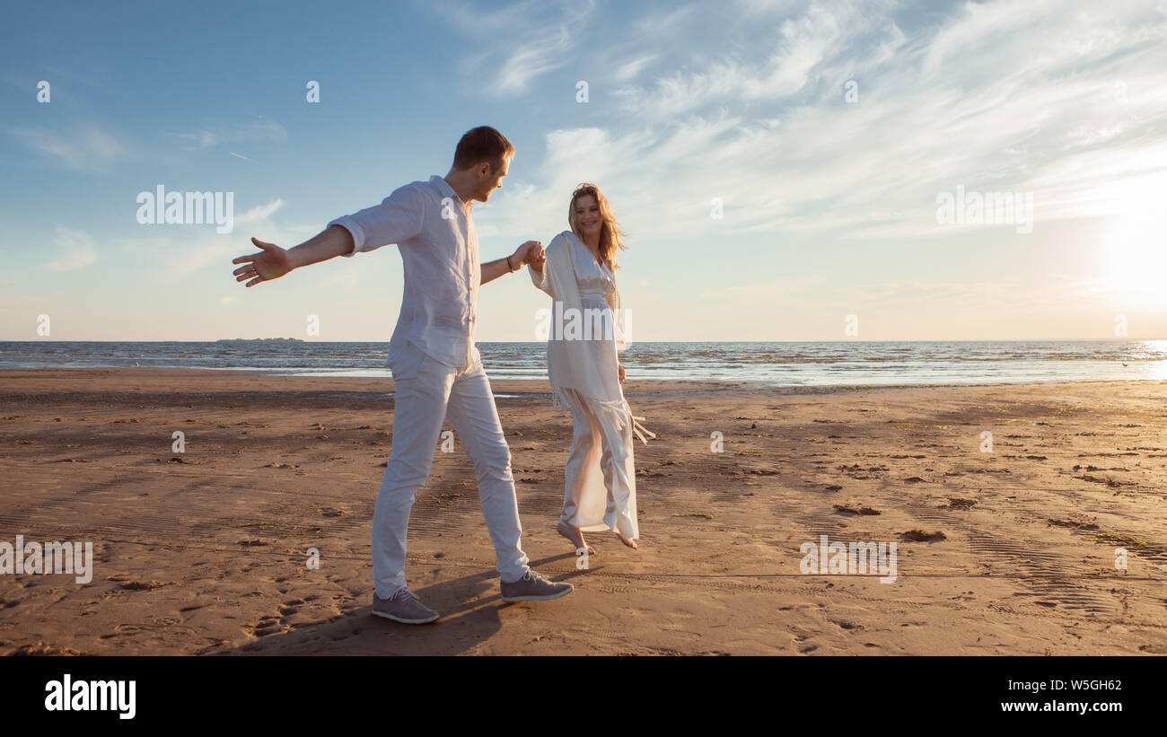 L Amour L Attente Pour Le Bebe Couple Femme Enceinte Et L Homme Blanc En Battant Les Vetements Marcher Tenir La Main Danse Contre La Toile De Fond De La Mer Au Coucher Du Soleil