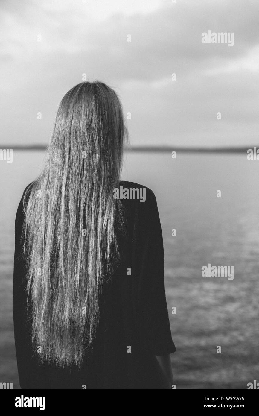 Long haired woman standing with dos à la caméra et à la recherche sur le lac Banque D'Images