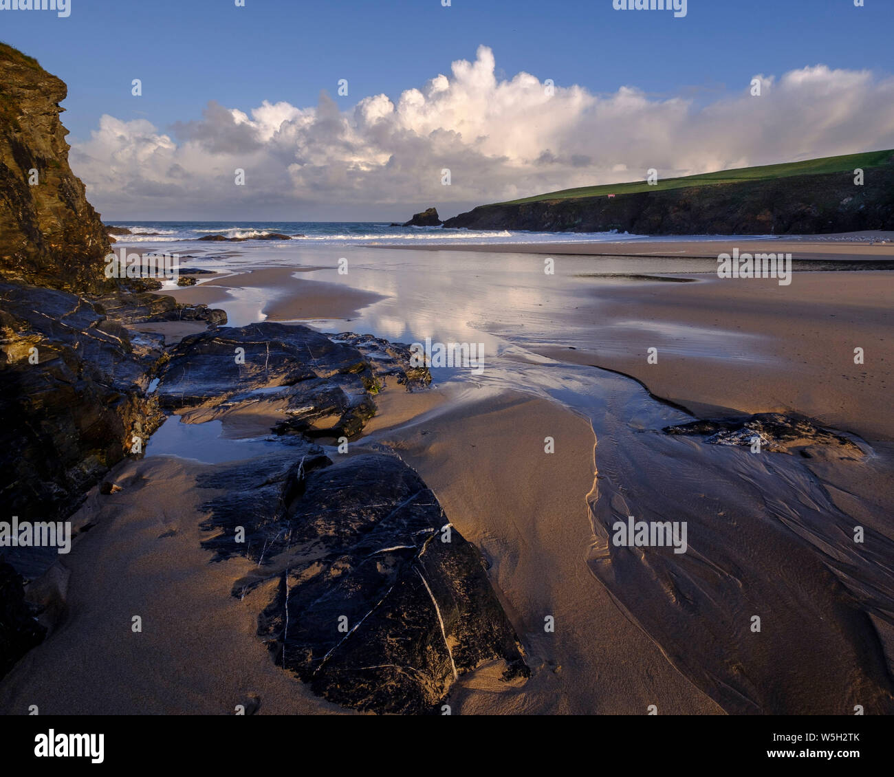 Les nuages de l'Atlantique représentent l'aube de la lumière sur le sable humide et les roches du Trevone, Padstow, Cornwall, Angleterre, Royaume-Uni, Europe Banque D'Images