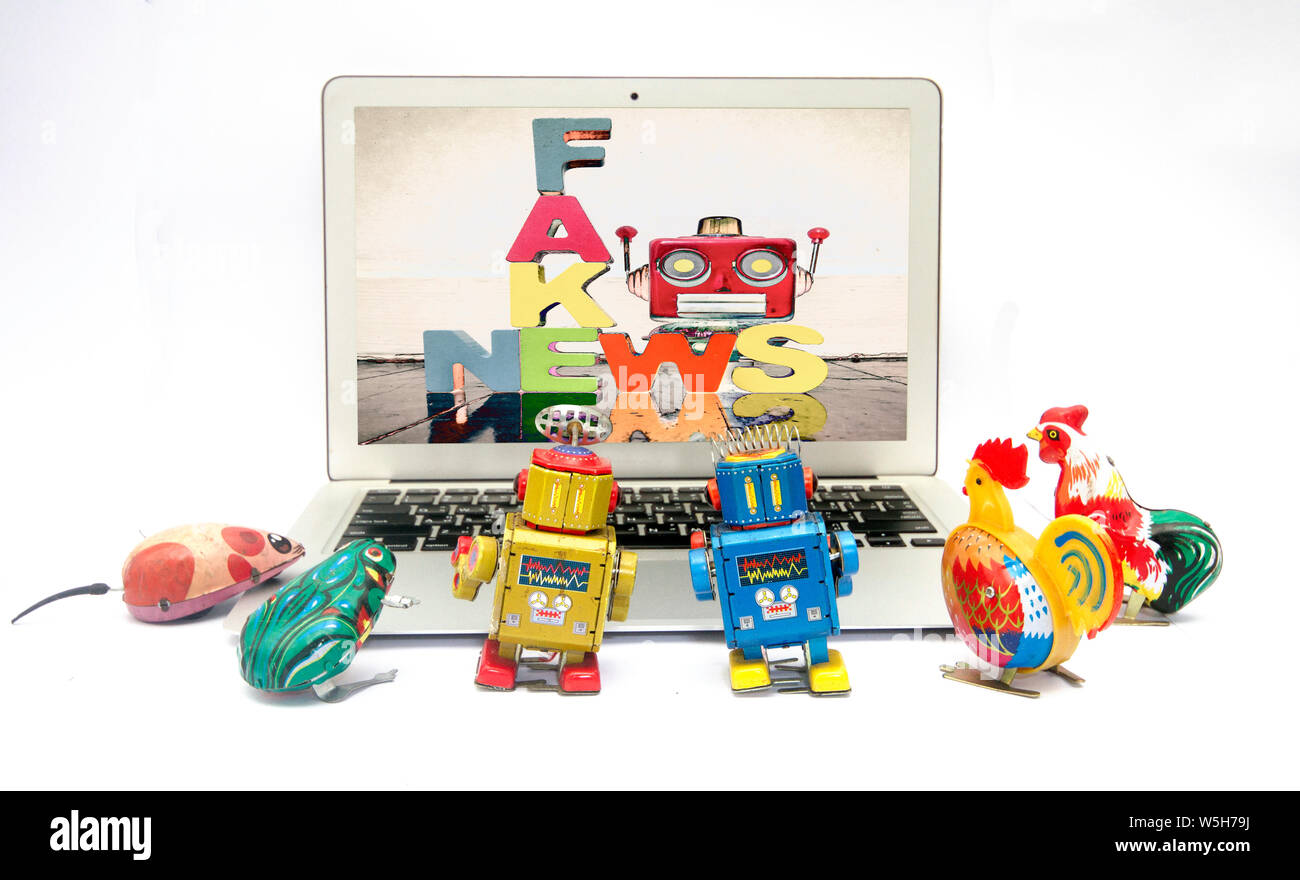Fake news concept avec la boîte de jouets rétro regarder les nouvelles sur un laptp Banque D'Images