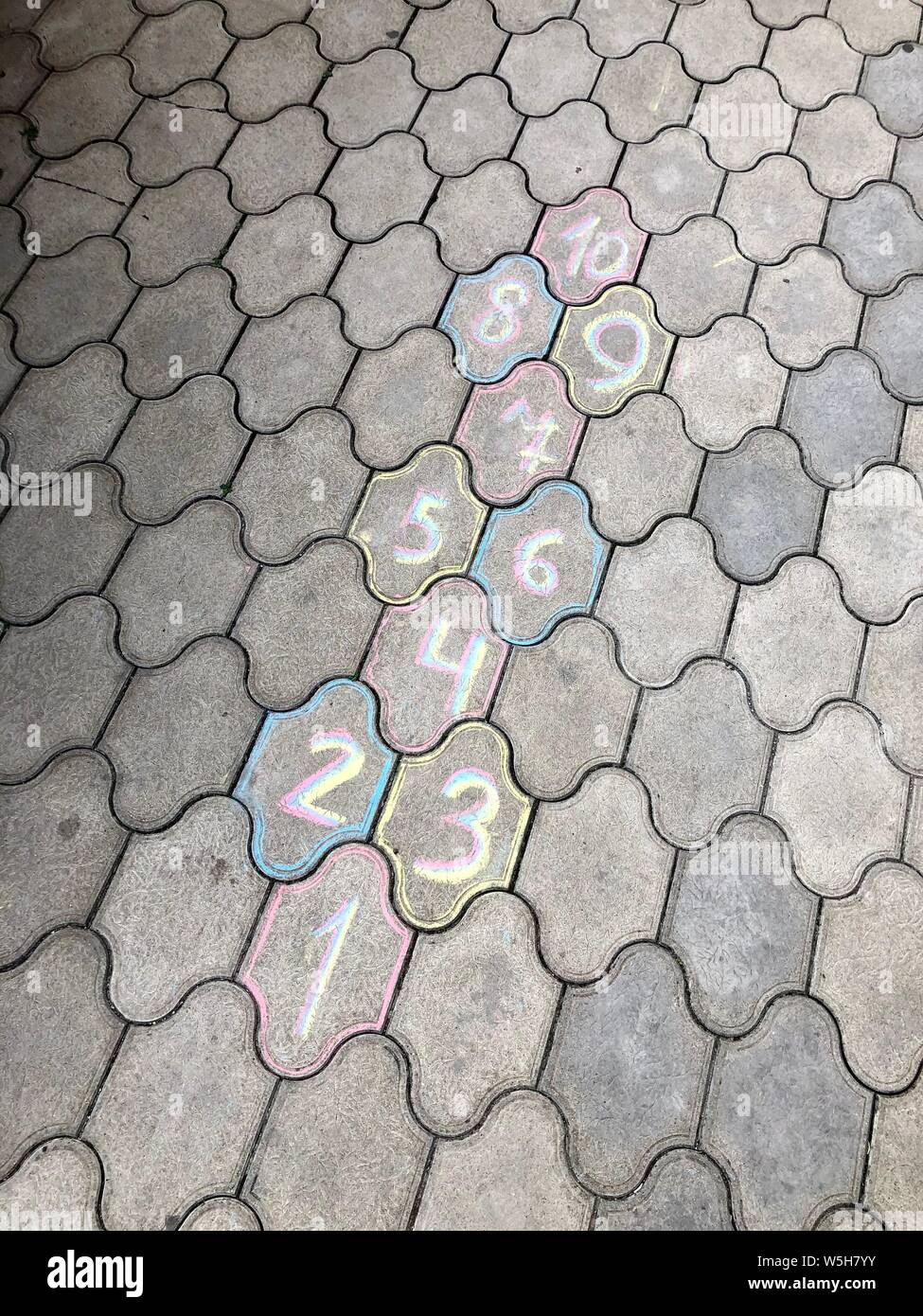 Les dessins sur l'asphalte pour aire de jeux. La marelle cour avec des numéros de 1 à 10 tirées avec craie blanche sur l'asphalte.enfant jouant à la marelle g Banque D'Images