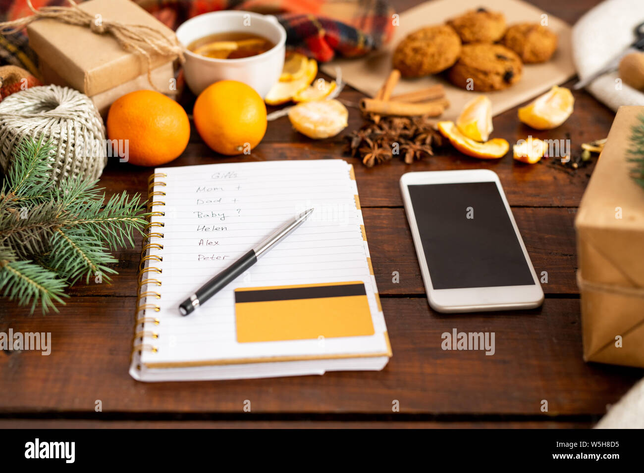 Smartphone, le bloc-notes page avec liste de cadeau, un stylo et une carte de crédit parmi les trucs de fête Banque D'Images
