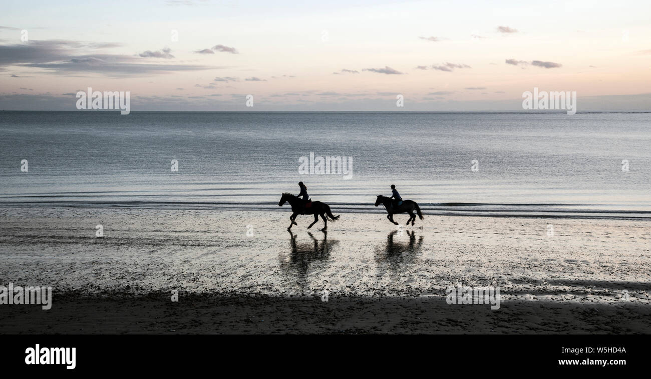 Cavaliers sur la plage le soir Banque D'Images