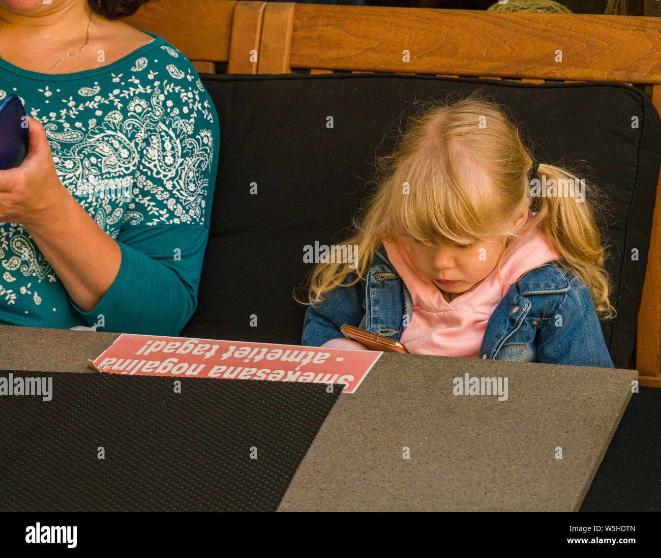 Mère et fille à la cafétéria de tâtonner téléphones cellulaires à Riga, Lettonie, Pays Baltes, de l'Union européenne. Banque D'Images