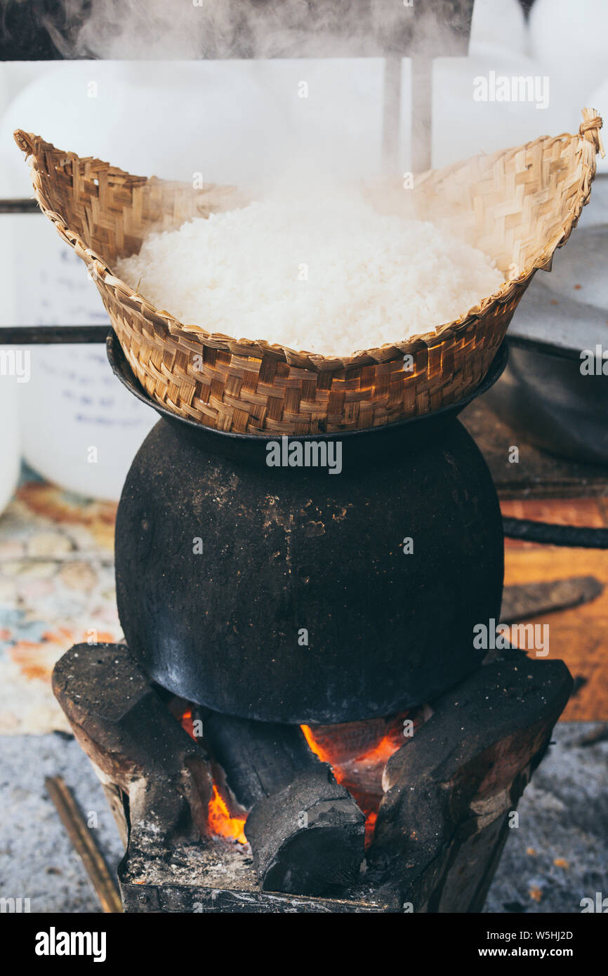 Cuisson du riz blanc vapeur laotien sur poêle à bois à Luang Prabang, Laos. Orientation verticale Banque D'Images