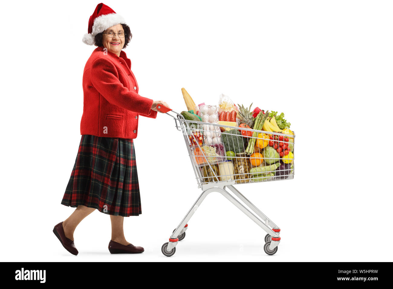 Tourné sur toute la longueur d'un senior woman with santa hat shopping pour les vacances de Noël avec un panier isolé sur fond blanc Banque D'Images