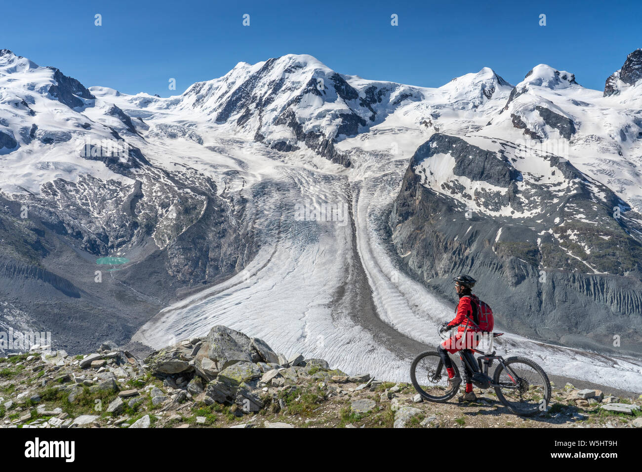 Active senior woman riding, son vtt électrique sur le Gornergrat dans Zermatt, Valais, Suisse. Dans l'arrière-plan glacier du Gorner, Monte Rosa Banque D'Images