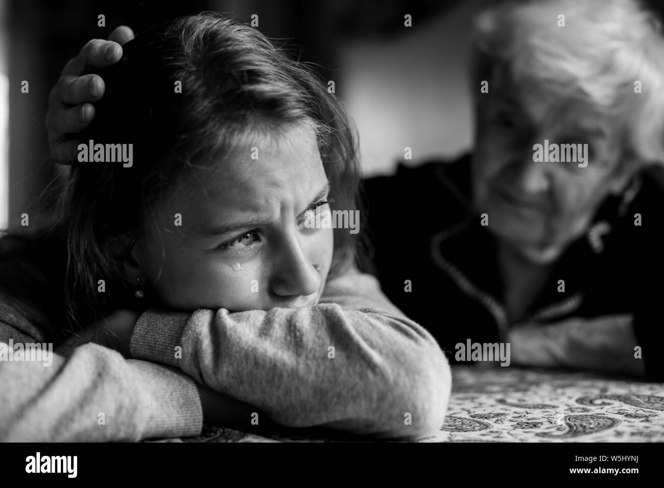 Vieille dame mamie réconfortant d'une petite fille pleurer sa petite-fille. Photo en noir et blanc. Banque D'Images