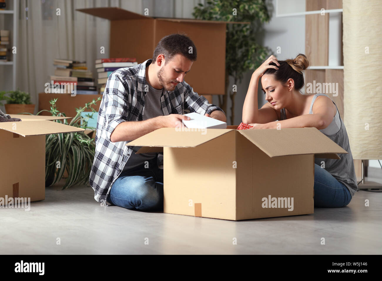 Expulsées triste couple moving home boxing biens assis sur le plancher dans la nuit Banque D'Images