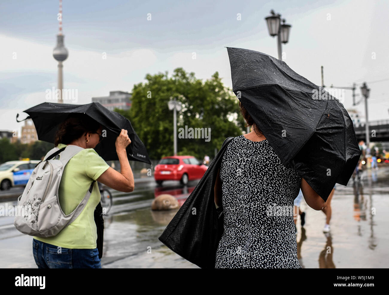 29 juillet 2019, Berlin : deux femmes tentent de se protéger de la pluie avec des parasols. Photo : Britta Pedersen/dpa-Zentralbild/dpa Banque D'Images