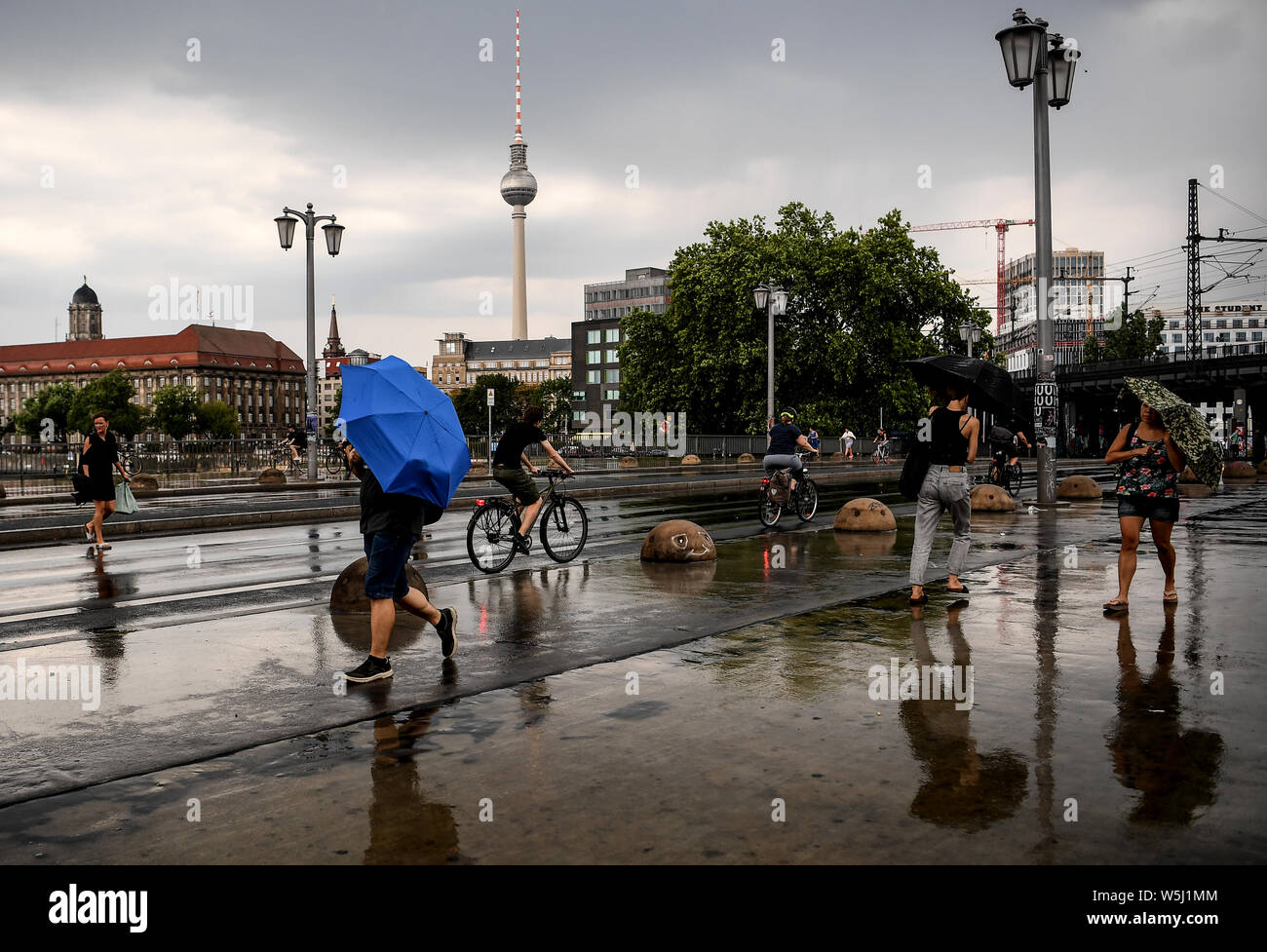 29 juillet 2019, Berlin : les passants tentent de se protéger avec des parasols. Photo : Britta Pedersen/dpa-Zentralbild/dpa Banque D'Images