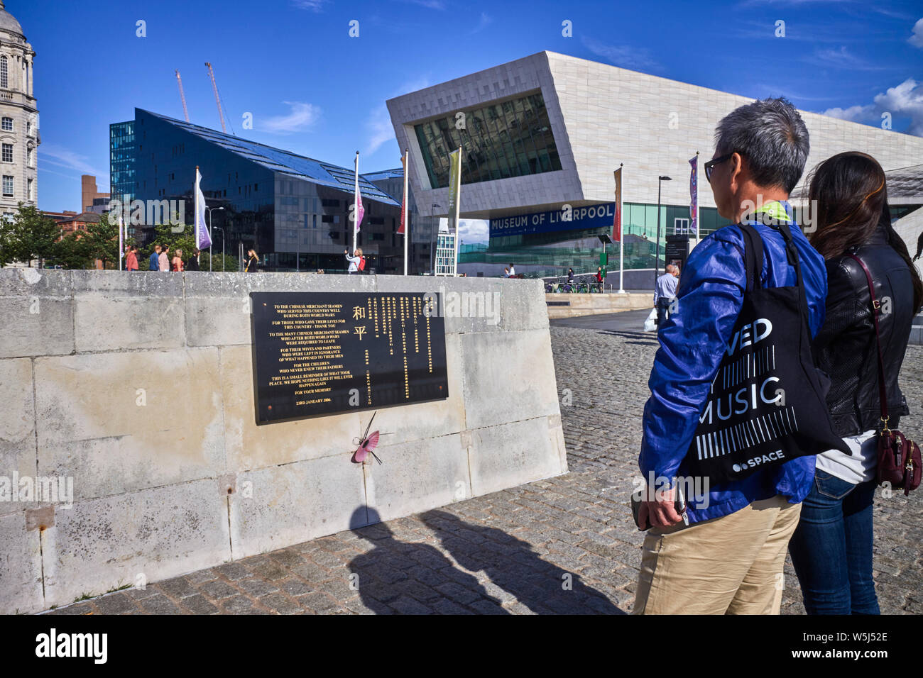 Les touristes chinois regarder sur le monument à la mémoire des marins chinois qui sont morts comme matelot de la marine marchande pendant la seconde guerre mondiale à Pier Head, Liverpool, Merseyside Banque D'Images