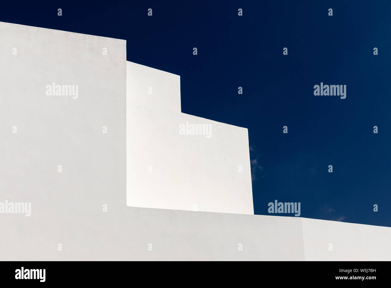 Résumé d'angles et de courbes de murs blancs et de dômes bleus de bâtiments à Megalochori, Santorini, Grèce Banque D'Images