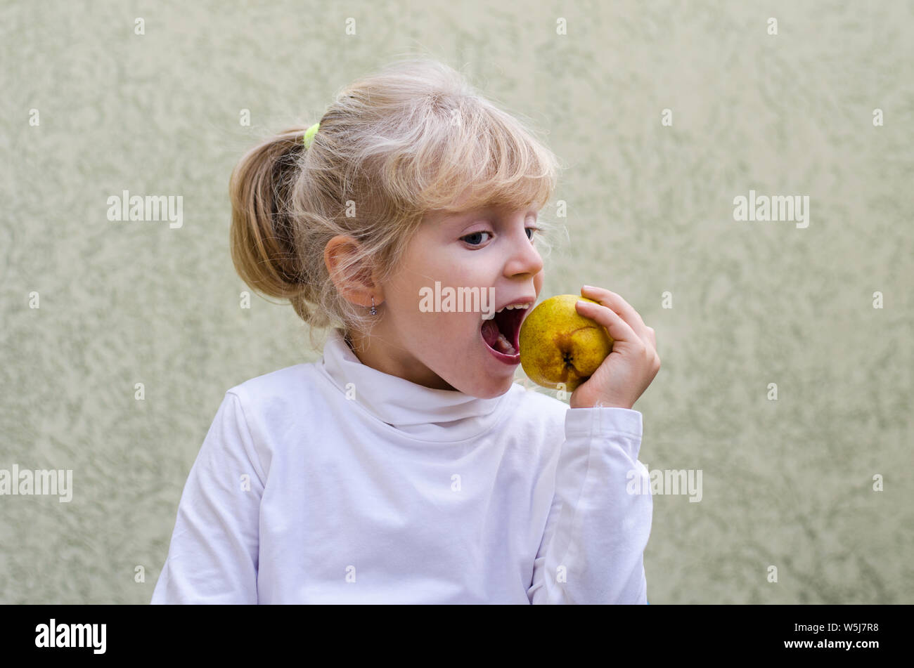 Blonde girl eating an apple Banque D'Images