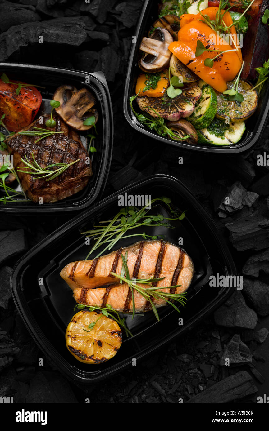 Close up de poissons grillés, de viande et de légumes dans des boîtes à emporter Banque D'Images