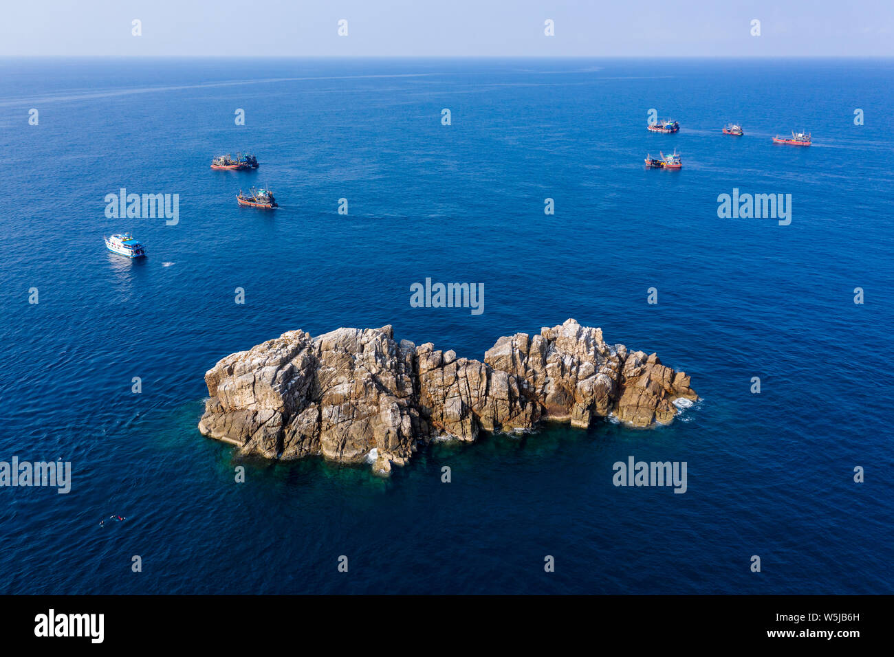 La surpêche - vue aérienne d'un bateau de plongée entouré de grands chalutiers de pêche industrielle autour d'un site de conservation au Myanmar Banque D'Images