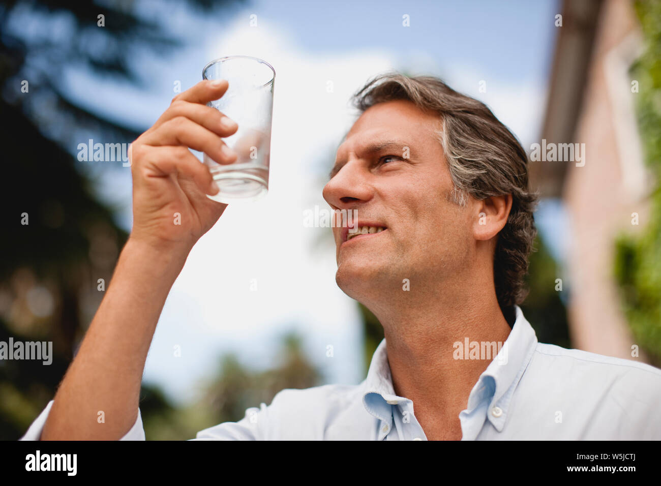 Homme mature boit un verre d'eau. Banque D'Images