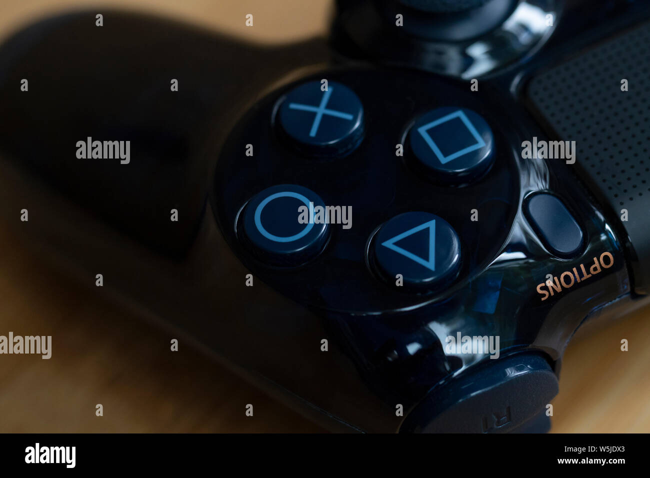 Anvers, Belgique - le 27 juillet 2019 : Un portrait de l'emblématique boutons de jeu d'une playstation 4 contrôleur sur une table en bois. Banque D'Images