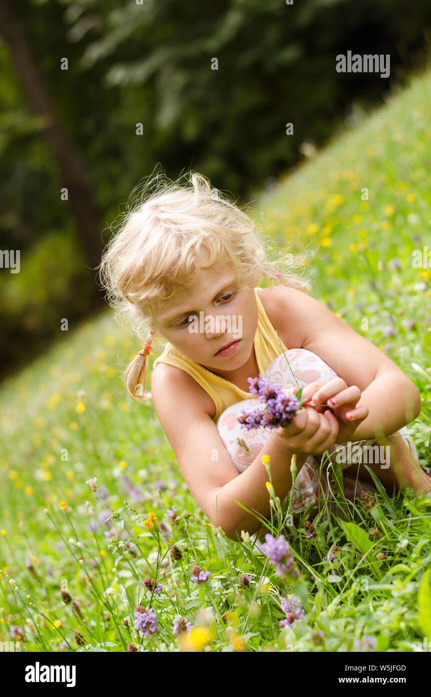 Belle fille blonde sitting on meadow Banque D'Images