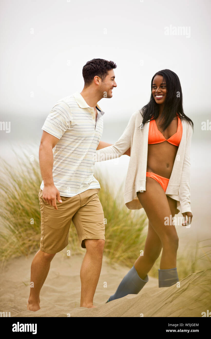 Smiling young couple marche à travers les dunes de sable. Banque D'Images