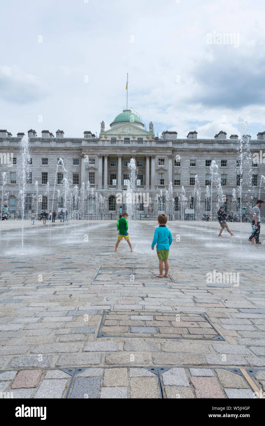 Enfants jouant dans l'eau des fontaines dans la cour intérieure de style néoclassique Somerset House, Londres, Angleterre, Royaume-Uni Banque D'Images