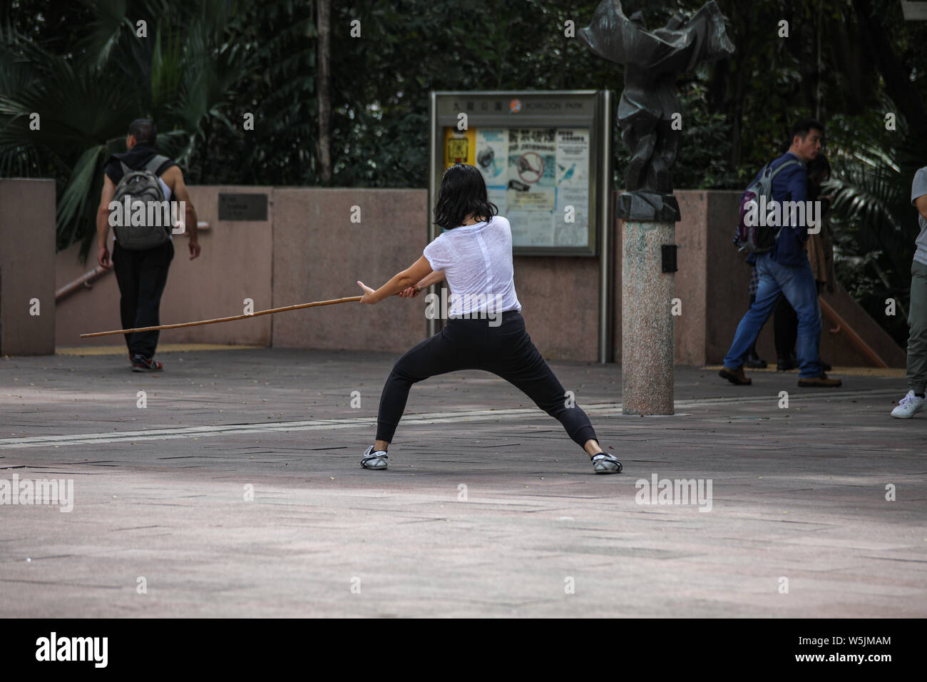 Jeune femme pratiquant avec bâton de kung fu Kung Fu au cour du parc de Kowloon, Hong Kong Banque D'Images