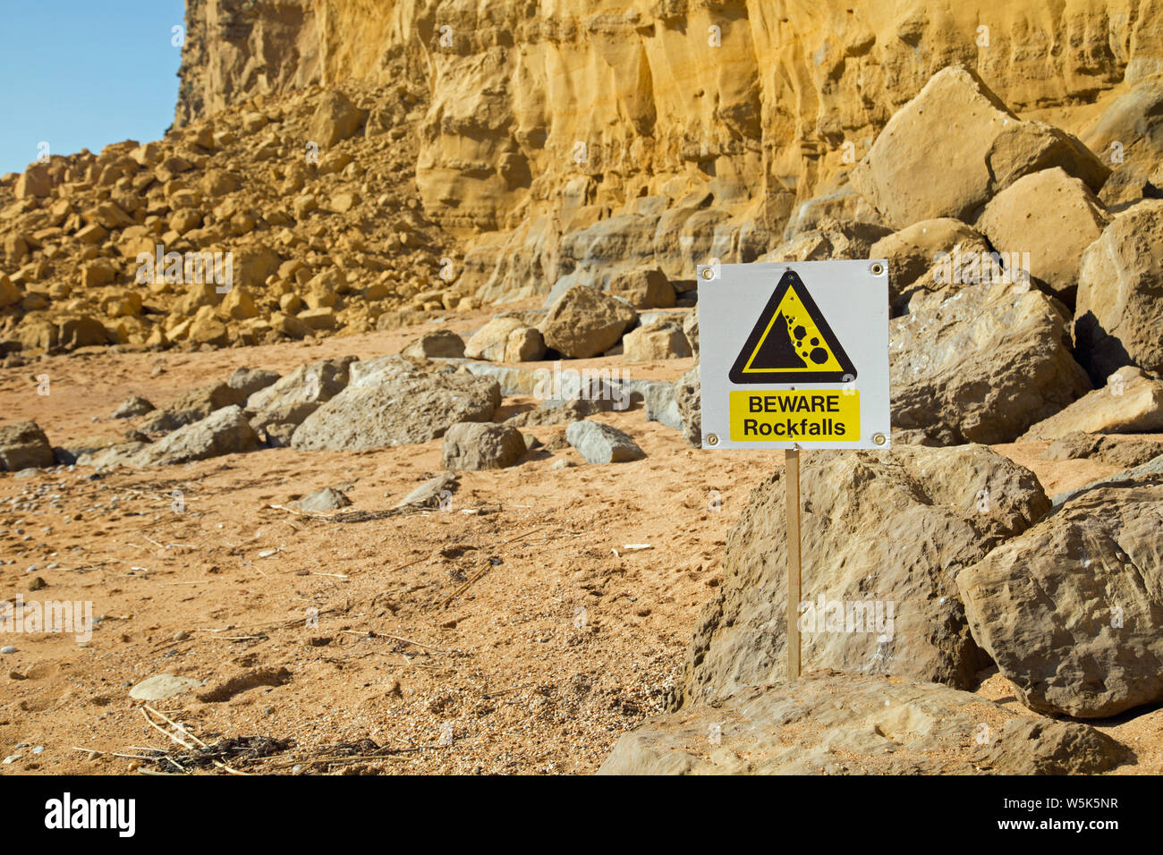 Un panneau d'avertissement indique à du danger de chutes de pierres depuis les falaises à Burton Bradstock, Dorset, Angleterre Banque D'Images